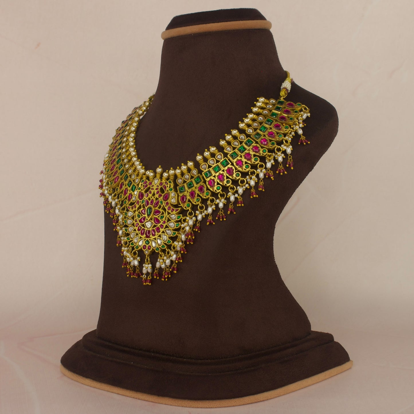 This is a Jadau Kundan short necklace with floral designs on it. This Neckpiece has ricepearls and ruby beads at bottom . This necklace is covered in 22k Gold plating