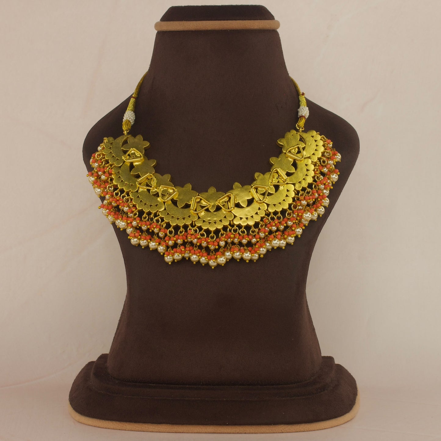 This is a Jadau Kundan Short necklace with flower designs. This is made in white jadau Kundan stones and coral stones. At the bottom of the necklace there are coral beads and pearls with 22k gold plating