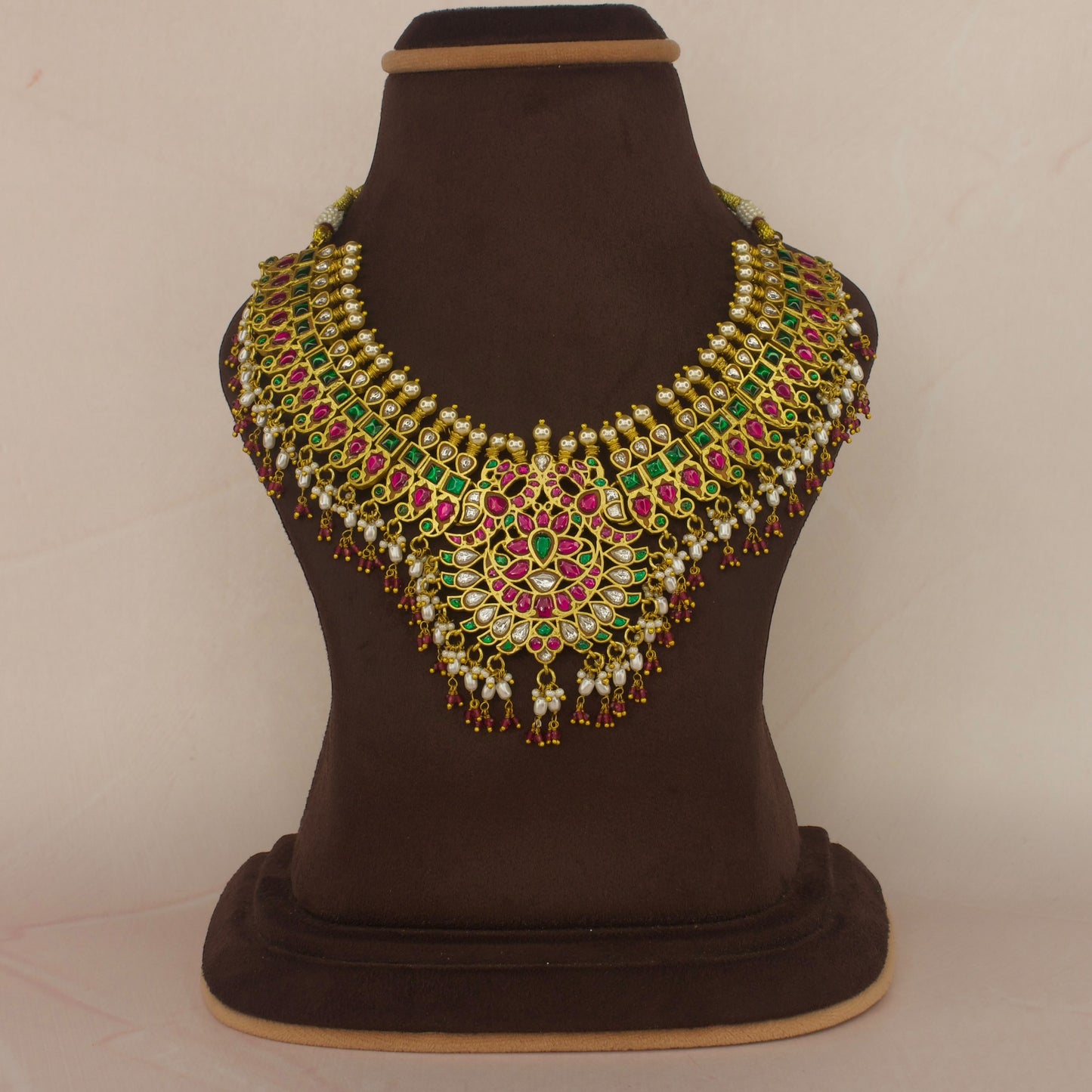 This is a Jadau Kundan short necklace with floral designs on it. This Neckpiece has ricepearls and ruby beads at bottom . This necklace is covered in 22k Gold plating
