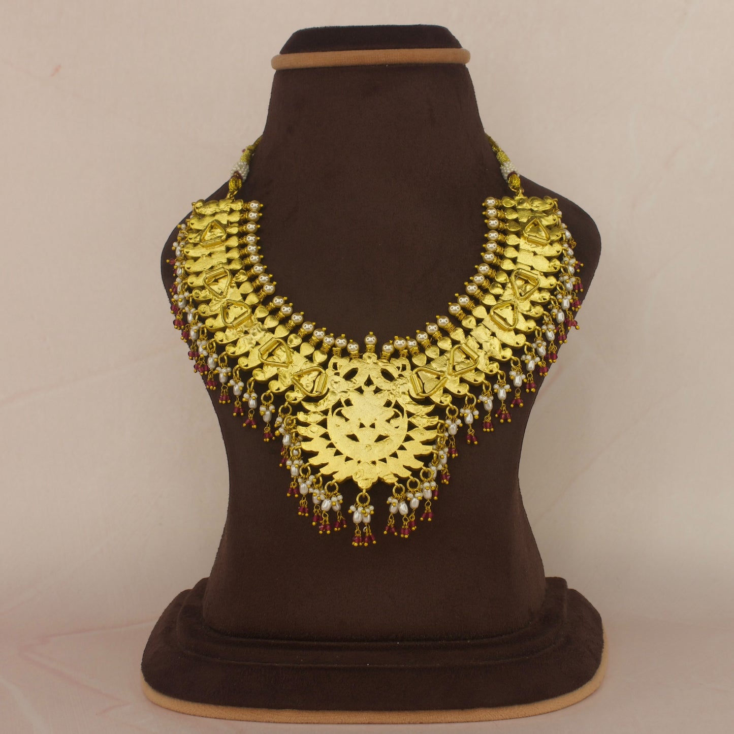This is a Jadau Kundan short necklace with floral designs on it. This Neckpiece has ricepearls and ruby beads at bottom . This necklace is covered in 22k Gold plating