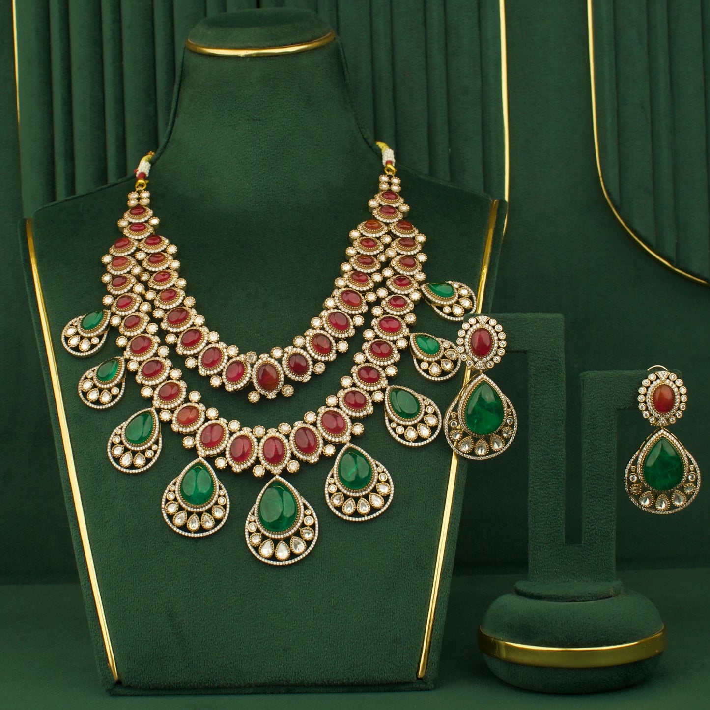 Ornate necklace with red and green gemstones on a green stand against a matching green background