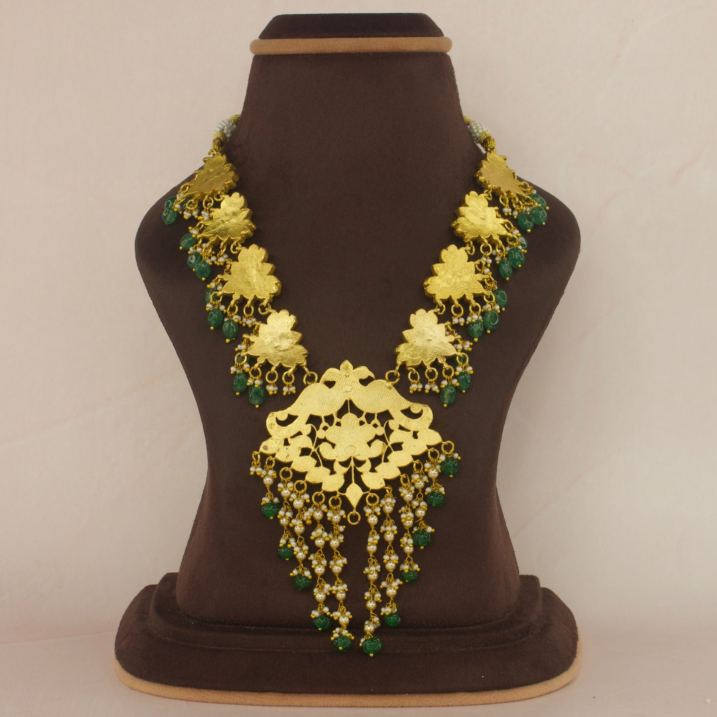 This is a Jadau Kundan Short Necklace, the Neckpiece has lotus designs all over it from the centre to the corners. This specific’s piece is with white Kundan stones and a singe green stone in the middle. The beads at bottom are Russian pumpkin beads.