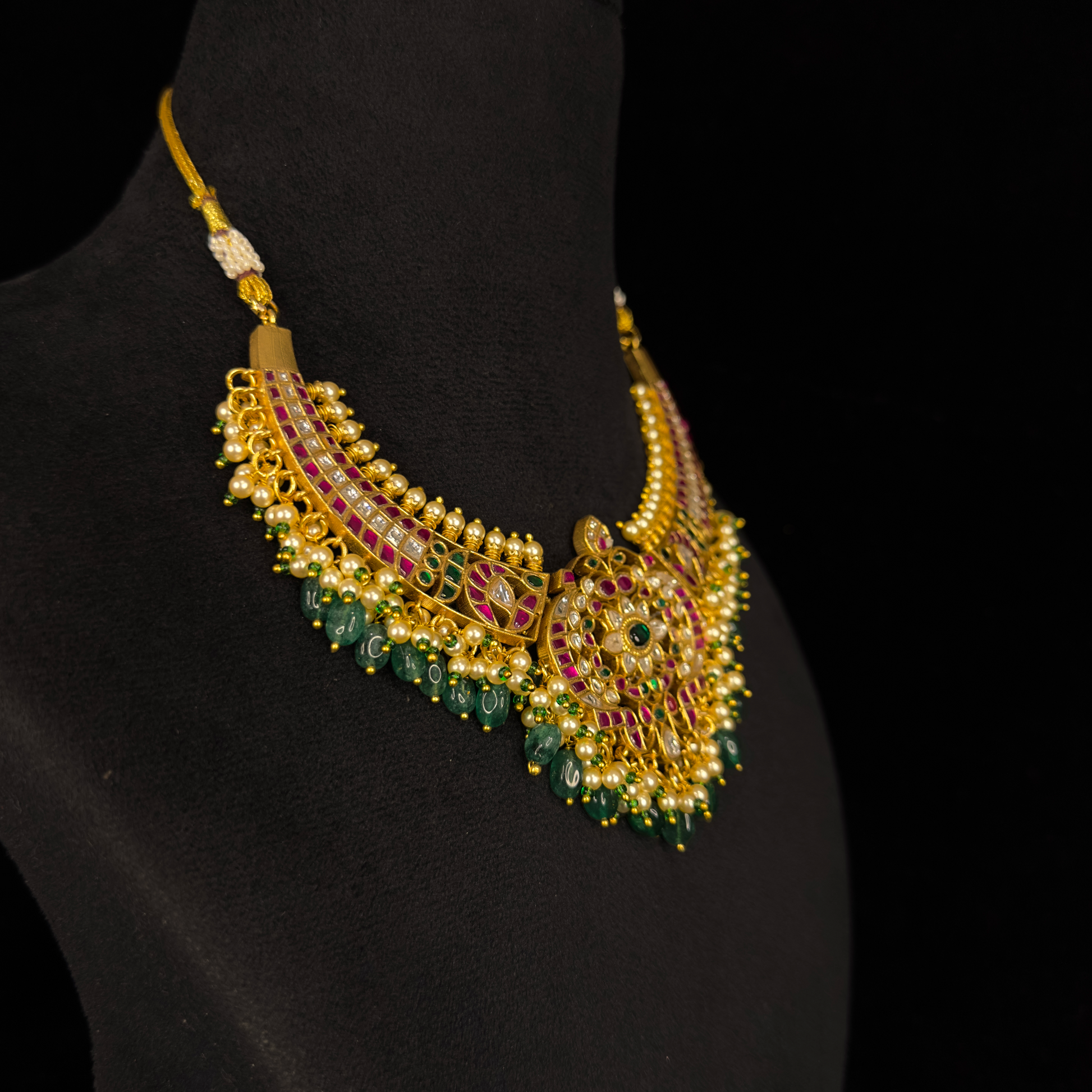 Opulent Charm: Jadau Kundan Necklace with Intricate Motifs and Emerald Drops with 22k gold plating This product belongs to jadau kundan jewellery category