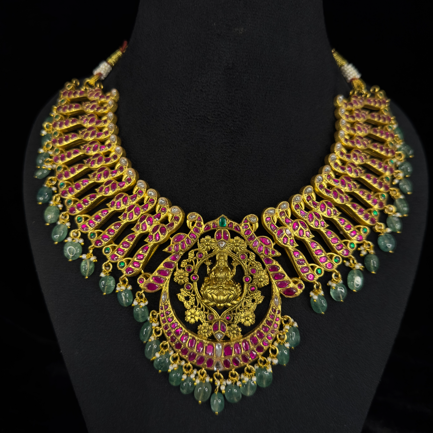 Regal Jadau Kundan Necklace with Goddess Lakshmi Motif and Emerald Bead Accents with 22k Gold plating This product belongs to Jadau Kundan jewellery category 