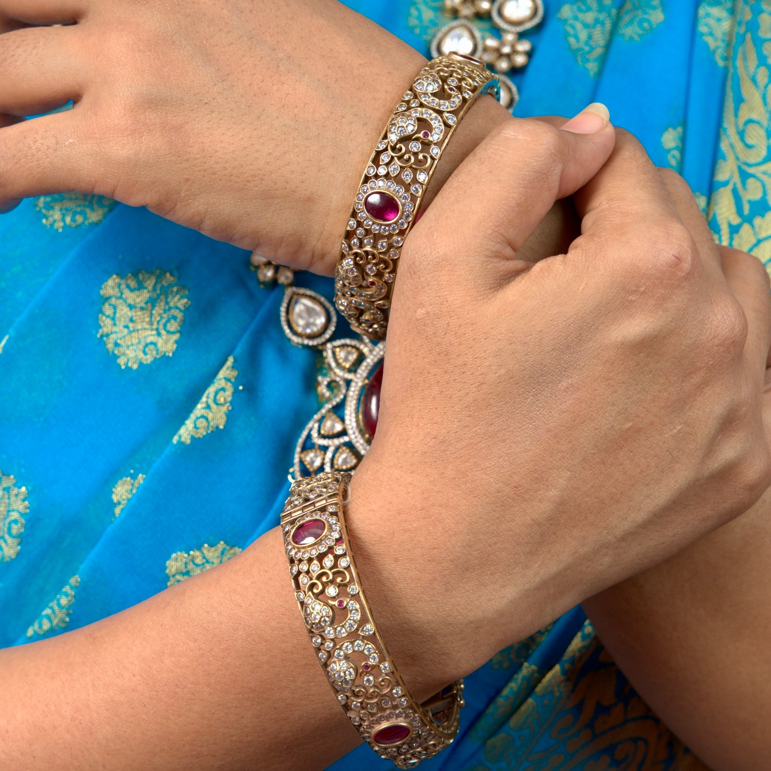 A woman wearing our Graceful AD stone Victorian plated Bangles with Peacock motifs. This Victorian Jewellery is available in a Red colour variant. 