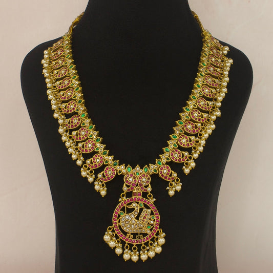 This is a Jadau Kundan Necklace with 22k Gold plating. This piece is with mango motifs and peacock motifs. There are Pearls at the bottom of the necklace