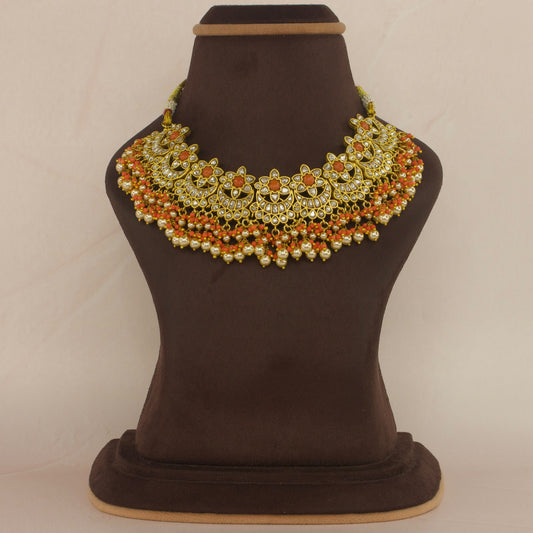 This is a Jadau Kundan Short necklace with flower designs. This is made in white jadau Kundan stones and coral stones. At the bottom of the necklace there are coral beads and pearls with 22k gold plating