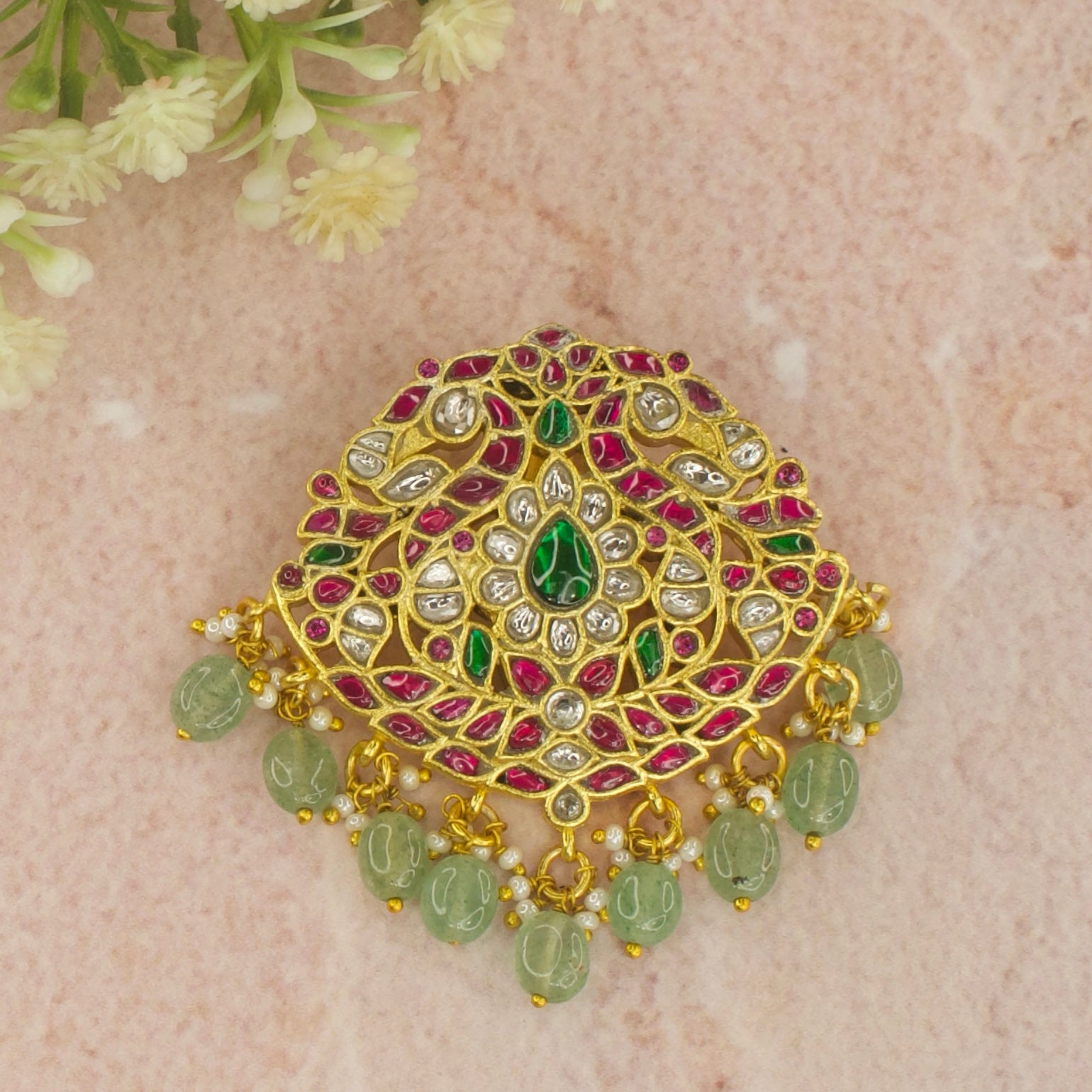 This is a Regal Jadau Kundan Pendant with Peacock motifs . The pendant is plated with 22k gold and at the bottom of the pendant we have Russian strawberry beads