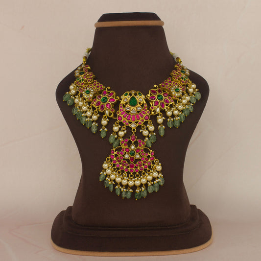 This is a Jadau Kundan short necklace with flower motifs and pearls and Russian emerald hangings. The piece is covered in 22k Gold plating