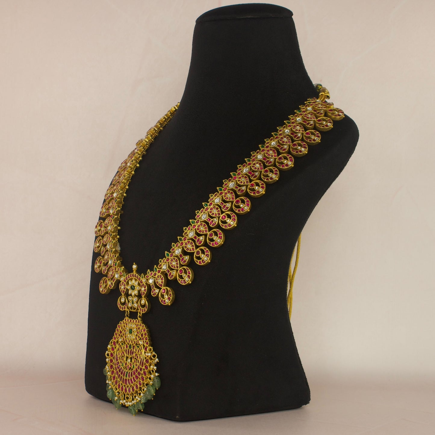 This is a Jadau Kundan Necklace with 22k Gold plating . This necklace has flower motifs and Russian emeralds at bottom