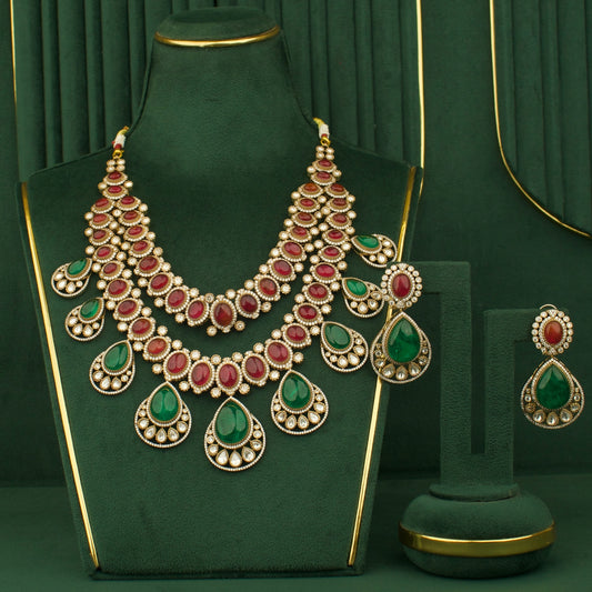 Ornate necklace with red and green gemstones on a green stand against a matching green background