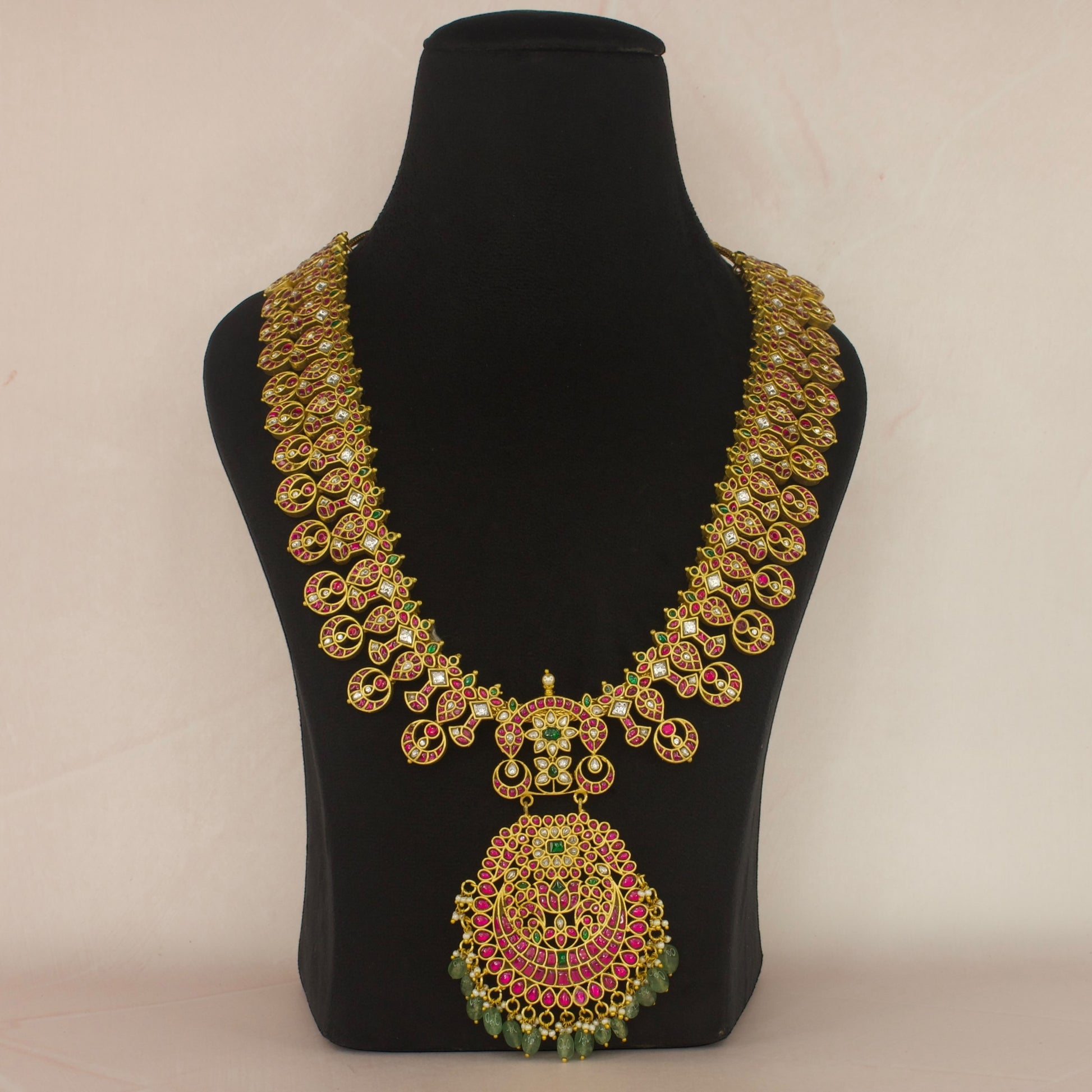 This is a Jadau Kundan Necklace with 22k Gold plating . This necklace has flower motifs and Russian emeralds at bottom