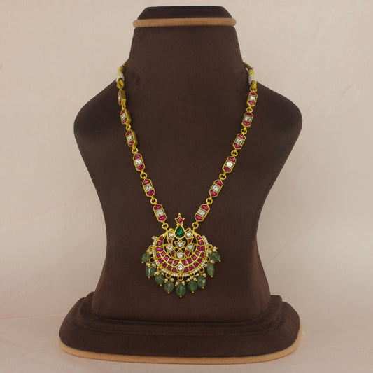Here is a short necklace suitable for any regal events. It has a flower design pendant with chain. It has jadau Kundan work on it with 22k gold plating. At the bottom are Russian emerald beads