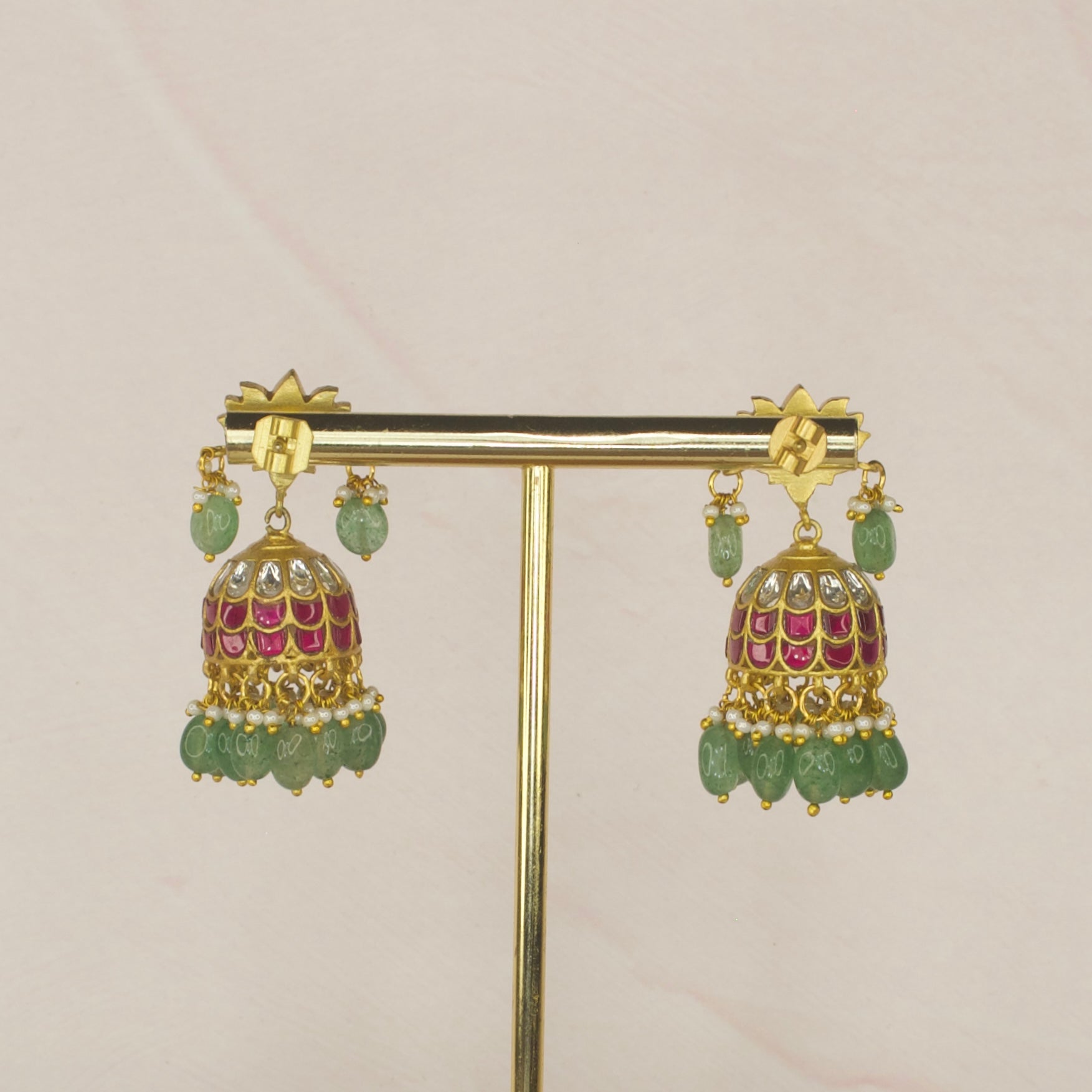 Serene Lotus Splendor Jadau Kundan Jhumkas with Emerald Accents with 22k gold plating. This product belongs to jadau Kundan jewellery