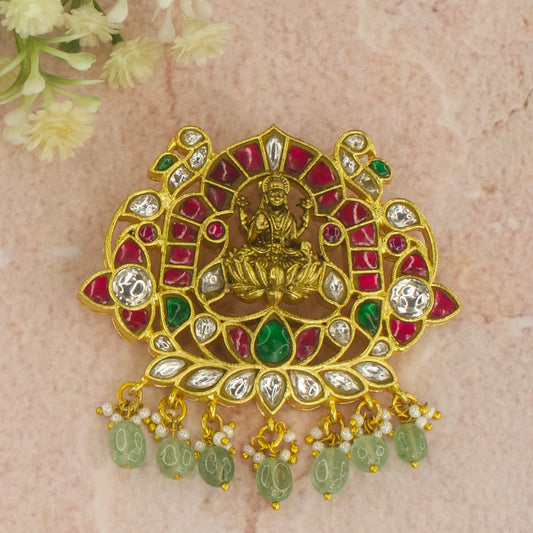 This a Jadau Kundan Pendant with Goddess Lakshmi motif finish in nakshi polish. This total pendant is covered in 22k gold plating and at the bottom of the pendant we have Russian emerald beads